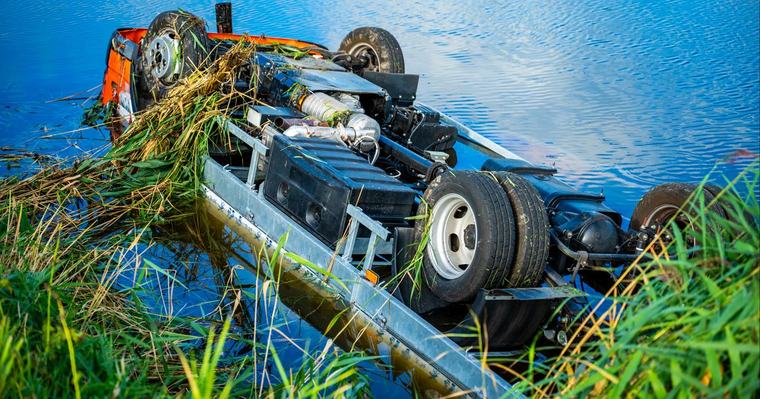 Bakwagen raakt van de weg en belandt op zijn kop in water