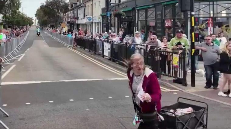 Drama maar net vermeden: vrouw met bolderkar steekt plots over, motoren en renners razen seconden later voorbij in Ronde van Groot-Brittannië