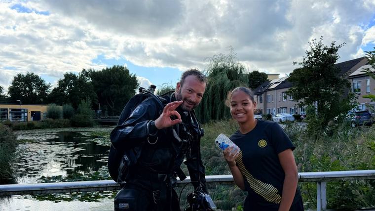 Tussen de blikjes in het water vist duiker Caithlin's werkende telefoon op